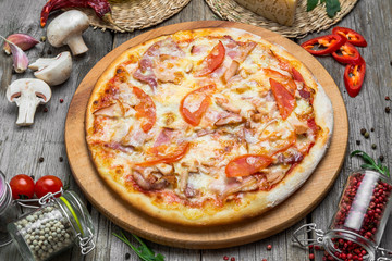 Pizza with tomatoes, mozzarella cheese, black olives and basil. Delicious italian pizza on wooden pizza board.