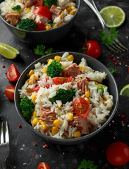 Fresh Tuna rice salad with sweet corn, cherry tomatoes, broccoli, parsley and lime in black bowl