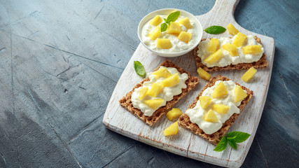 Homemade Crispbread toast with Cottage Cheese and Pineapple on white wooden board.