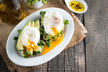 Avocado toast, cherry tomato on wooden background. Breakfast with toast avocado, vegetarian food, healthy diet concept. Healthy sandwich with avocado and poached eggs.