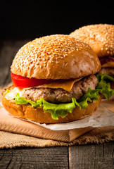 Close-up photo of home made hamburger with beer made of beef, onion, tomato, lettuce, cheese and spices. Fresh burger closeup on wooden rustic table with potato fries and chips.