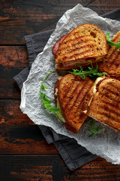 grilled sandwich with turkey, bacon, tomato and cheese on rustic wooden background