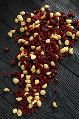 Healthy snack of Dried cranberries and macadamia nuts in a ceramic bowl on rustic wooden table