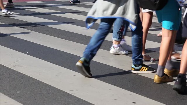 A lot of people are crossing the street at a crosswalk. feet closeup