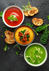 Variety of cream soup bowls: sweet pea and mint, tomato and basil and butternut squash with steamed kale and fried halluomi