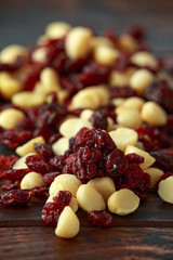 Healthy snack of Dried cranberries and macadamia nuts in a ceramic bowl on rustic wooden table