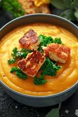 Baked butternut squash and carrot cream soup with steamed kale and fried halluomi