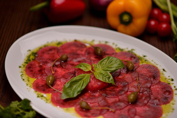 carpaccio with basil and capers on a white plate