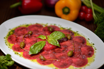 carpaccio with basil and capers on a white plate