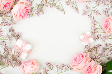 Rose fresh flowers with leaves and gift boxes frame on table from above with copy space, flat lay scene