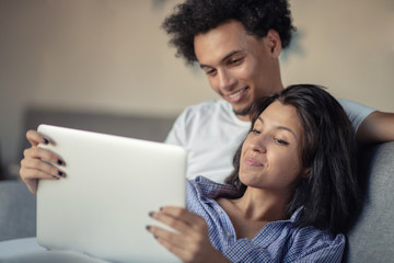 Young attractive diverse couple browsing internet, using laptop computer, smiling.