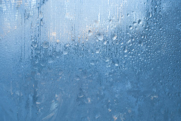 Frozen small water jets and drops on the winter window. 
