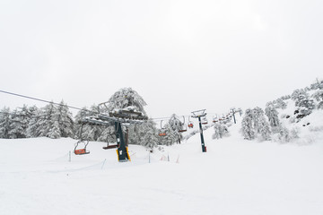 Ski lifts and cable cars going up the mountain bringing snowboarders to ski slopes.