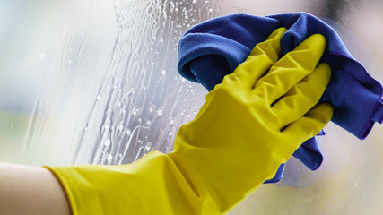 Gloved hand cleaning window rag and spray