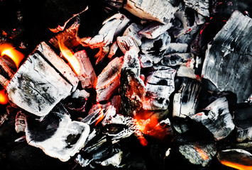 Smoldering embers of fire, live coals, burning charcoal in the background texture, closeup, glowing coal