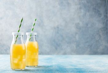 Fresh pineapple juice and ripe pineapple on grey background