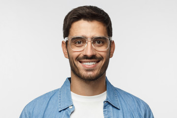Close up shot of smiling handsome man in blue denim shirt and trendy trasparent glasses isolated on...