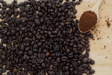 coffee beans and powder coffee in spoon on a wooden background.