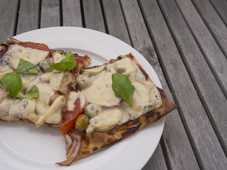Home made Close up from above on italian freshly home made organic pizza with tomatoes, cheese, onion, olives and green basil leaves on white plate on vintage wood table background