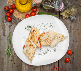 Shawarma sandwich or lavash with fresh vegetables and sauce on the gray plate decotated with cherry tomatoes, basil leaves on the gray table.