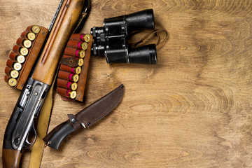 Hunting rifle and ammunition lie on wooden background. Copy space