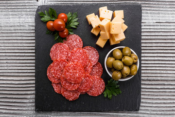 delicious sliced salami on a stone plate wooden background