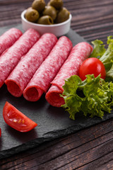 delicious sliced salami on a stone plate wooden background