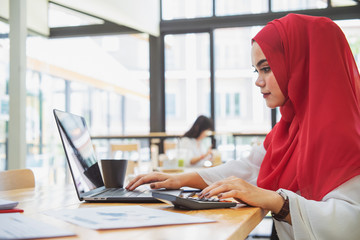 Fototapeta na wymiar Attractive female Arabic corporate worker working on laptop computer on desk 