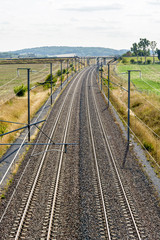 Fototapeta na wymiar View from above of a french high speed railway track with overhead line equipment, made of posts, catenaries, wires and power lines to supply bullet trains.