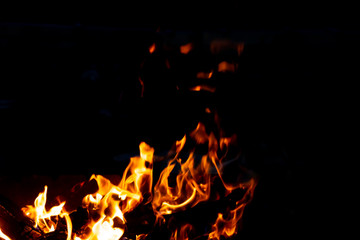 Fototapeta na wymiar Flames of fire from burning coals in the grill late at night.