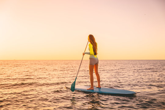 Young Woman Floating At Stand Up Paddle Board With Warm Sunset Colors