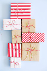 A lot of christmas presents wrappend in red, white and craft paper tied with baker's twine string. Multiple new years gifts in different wrapping. Top view, close up, copy space, background, flat lay.
