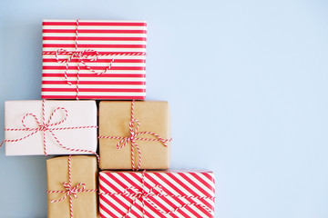 A lot of christmas presents wrappend in red, white and craft paper tied with baker's twine string. Multiple new years gifts in different wrapping. Top view, close up, copy space, background, flat lay.