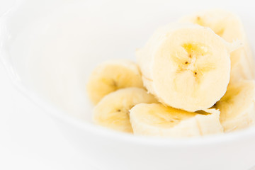 sliced banana fruit top view in ceramic plate isolated on white background. healthy vegetarian nutrition food. exotic summer harvest.