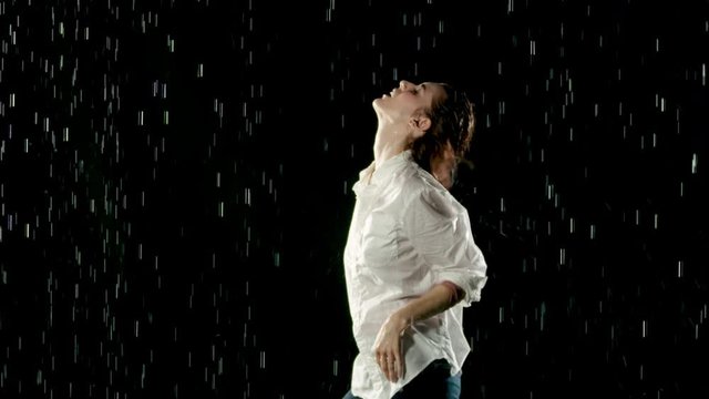 Beautiful woman dancing in the rain. Slow Motion.