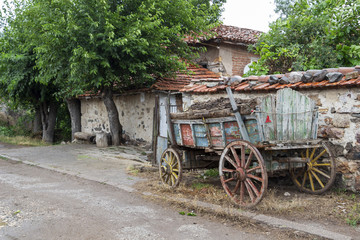 A loaded with compost colored old cart in front of a house at the Rhodope Mountains village of...