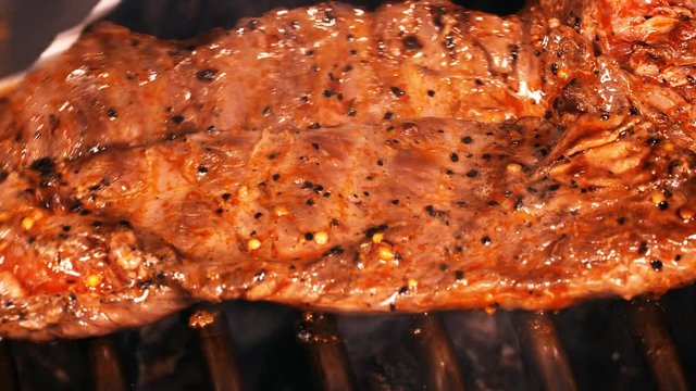 UHD slow dolly shot of juicy Mexican style marinated beef steak on the grill with flames and smoke