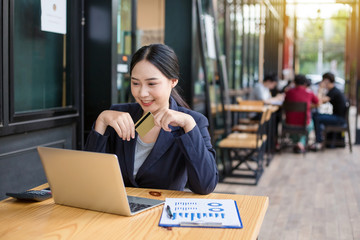 Young woman smiling. Business woman holds credit card and using laptop. Online shopping concept