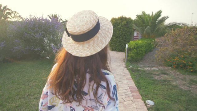 Beautiful woman walking near old luxury villa in Italy. Nice hotel territory.  Girl Dressed in hipster clothes. Female tourist.Elegant girl have good moments. Following camera. Back view