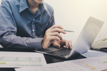 Young businessman using laptop analysis of investment are in his office.