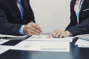 Hand of businessman holding the pen point to the graph information during discussion at meeting