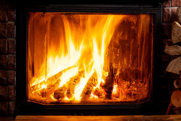 Old wooden table and fireplace with warm fire at the background.