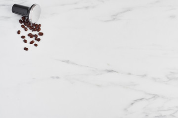 Top view of black coffee tamper and roasted coffee beans on white marble background. Flat lay with copy space.