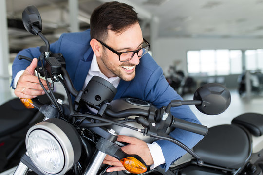 Fototapeta Young happy handsome man choosing a new motorcycle at motorcycle showroom.