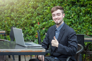 Young businessman successful using the laptop sitting working in the outdoor cafe happily.