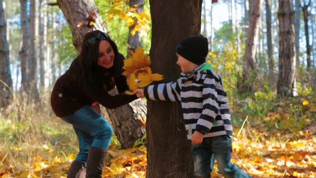 A woman is playing with a child in an autumn forest. Slow motion.