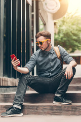 Traveler and tourist  young man wearing backpack wearing yellow glasses using smartphone. travel backpack concept.