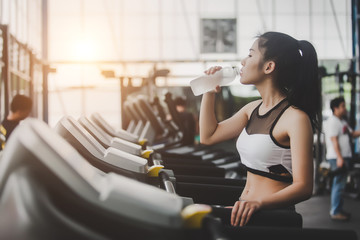 Woman drinking water after workout exercising in the gym