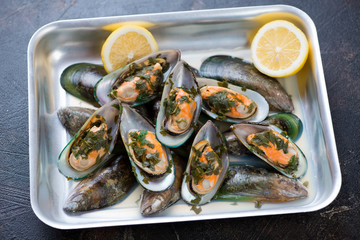 Oven-tray with green mussels stewed in white wine with addition of parsley and lemon, horizontal shot