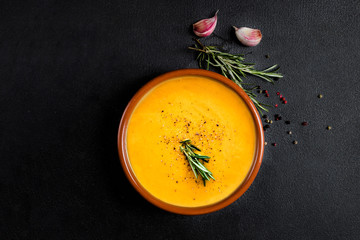 Pumpkin and carrot  Cream soup on  black board  background. Autumn cream-soup in country style. Top view. Copy space.
